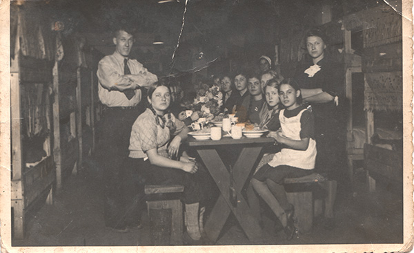 Судя по одежде и столу, на фотографии запечатлён какой-то праздник. Стоящие по бокам от женского (и детского) «населения» барака мужчина и женщина — надзиратели. Дело 192871.